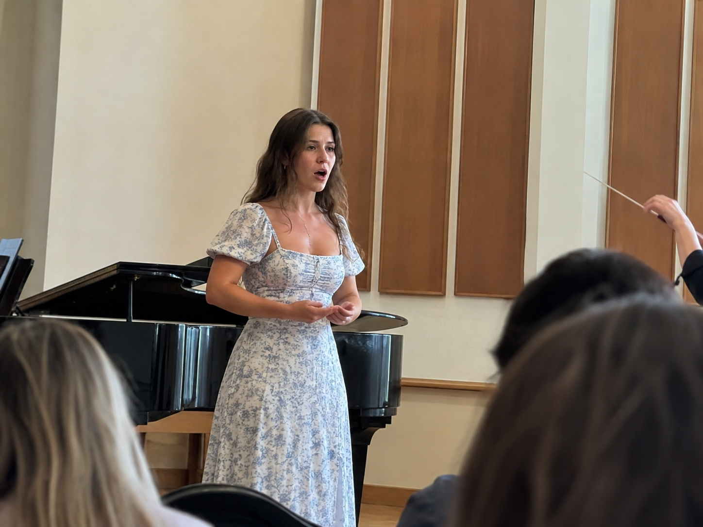 A singer performing beside a piano for an audience